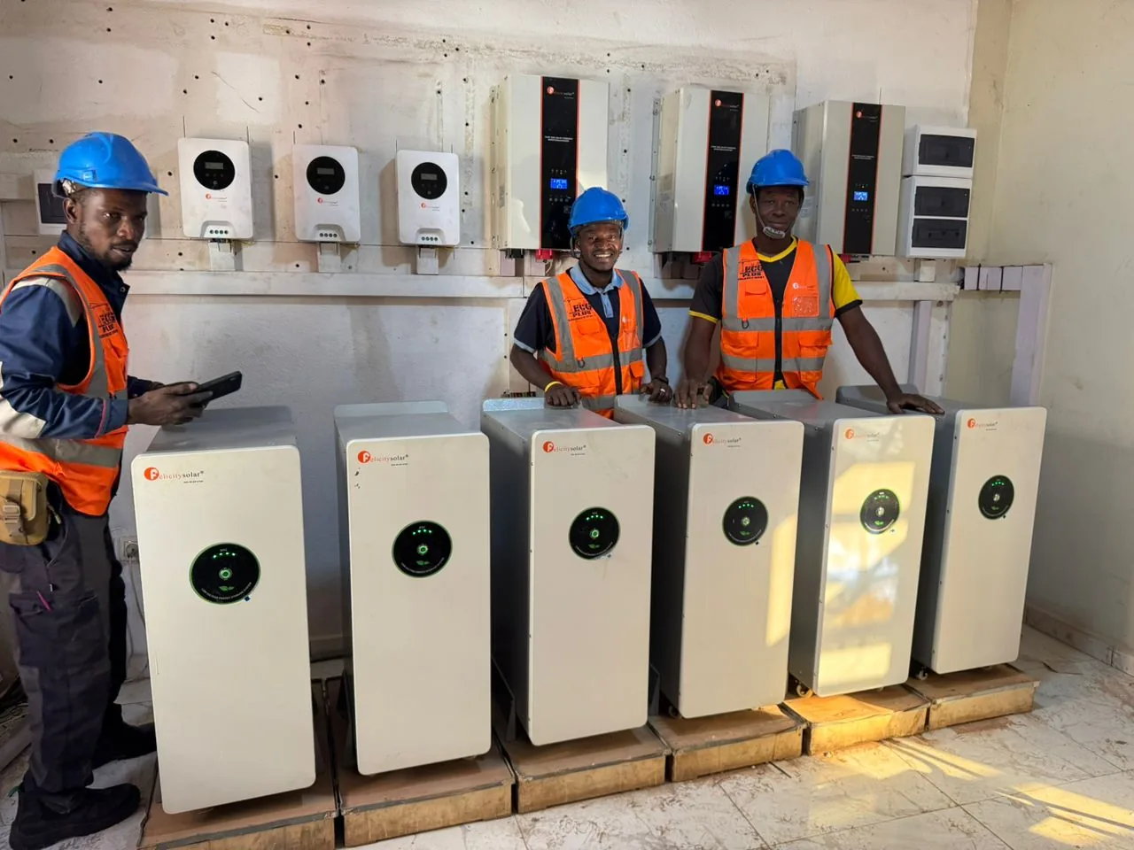 Trois membres de l’équipe avec des casques et des gilets ECG PLUS, devant des équipements électriques.